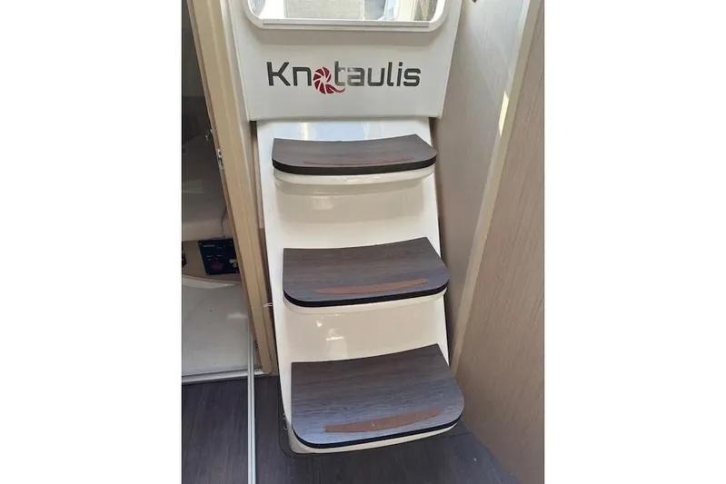 Knotaulis Yacht Photos Pics Staircase inside 2023 Beneteau Oceanis 34.1 yacht, featuring wooden steps and "Knotualis" branding.