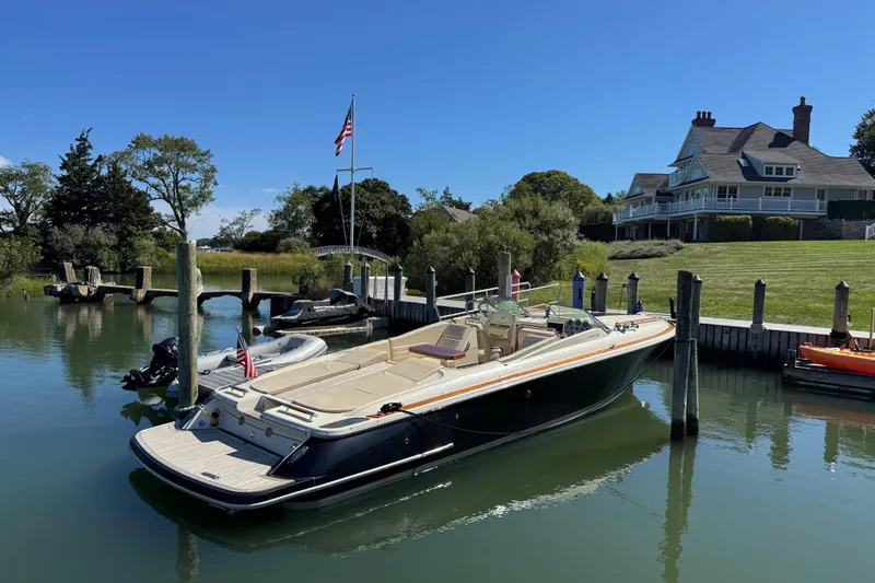  Yacht Photos Pics 2015 Chris-Craft Corsair 32 docked near a waterfront house, under clear blue skies.