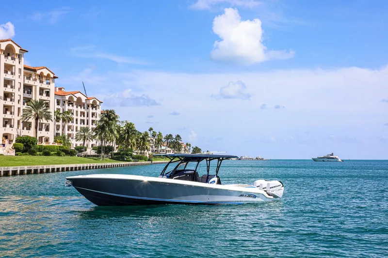 Knotty G Yacht Photos Pics 2020 Nor-Tech 340 boat cruising near waterfront buildings under a clear blue sky.