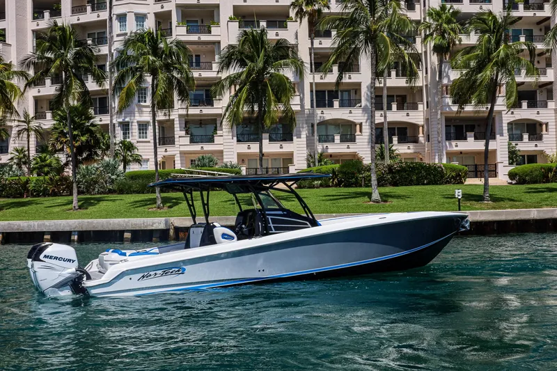 Knotty G Yacht Photos Pics 2020 Nor-Tech 340 boat cruising near waterfront apartments with palm trees.