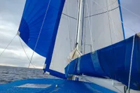 Blue sails of a 2008 Custom Trimaran Polynésie 42 on open sea.