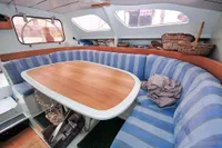 Interior of 2008 Custom Trimaran Polynésie 42 with striped seating and wooden table.