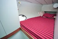 Cozy cabin interior of 2008 Custom Trimaran Polynésie 42 with striped bedding.