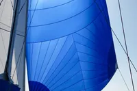 Custom Trimaran Polynésie 42 sailing with vibrant blue sail on open sea, 2008 model.