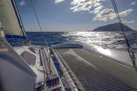Sailing on a 2008 Custom Trimaran Polynésie 42 under sunny skies, ocean view.