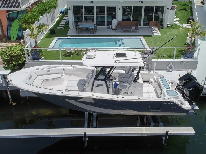  Yacht Photos Pics 2024 Sea Fox 328 Commander boat docked near a modern waterfront home with pool.