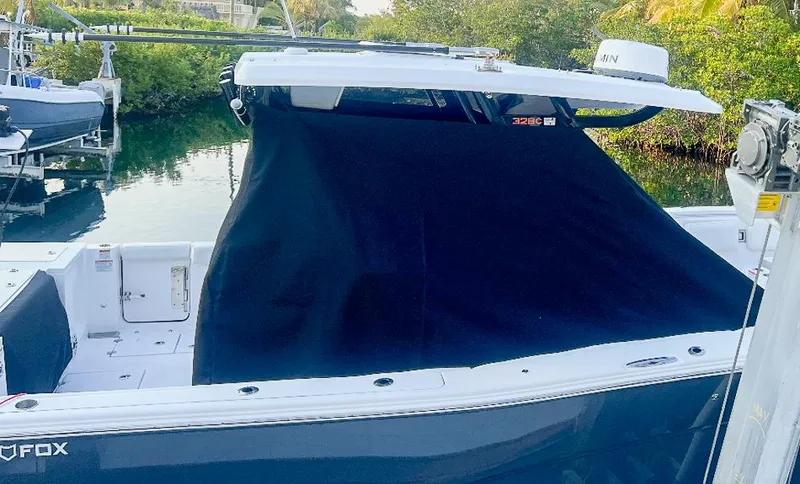  Yacht Photos Pics 2024 Sea Fox 328 Commander boat docked with black cover, surrounded by greenery.