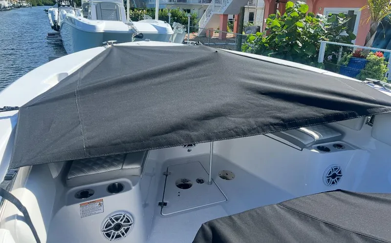  Yacht Photos Pics 2024 Sea Fox 328 Commander boat with black sunshade, docked near lush greenery.