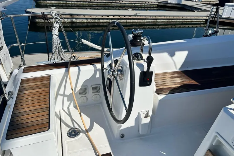 Toofun Yacht Photos Pics Cockpit of 2016 Beneteau Oceanis 38 sailboat with steering wheel and wooden seating.