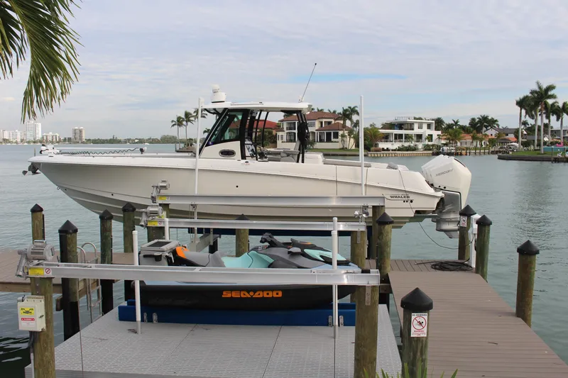  Yacht Photos Pics 2020 Boston Whaler 350 Outrage docked on a lift, with scenic waterfront view.