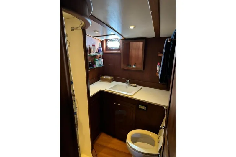  Yacht Photos Pics Compact wooden boat bathroom with sink, toilet, and storage shelves, Don Brooke 77, 1987 model.
