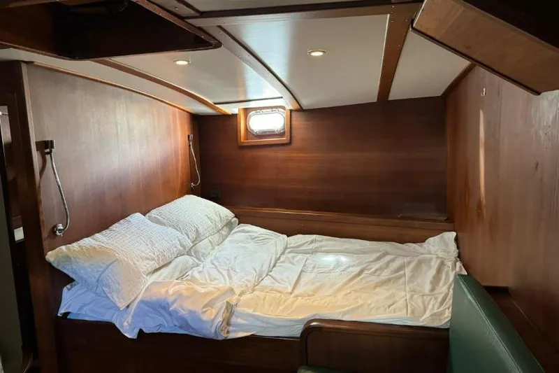  Yacht Photos Pics Cozy wooden cabin interior with bed, porthole, and soft lighting on a 1987 Don Brooke 77.