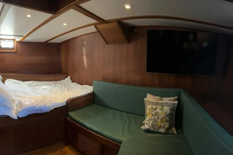  Yacht Photos Pics Cozy cabin interior of 1987 Don Brooke 77 yacht with bed, sofa, and TV.
