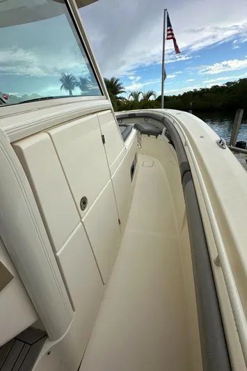  Yacht Photos Pics 2017 Scout 350 LXF boat deck with American flag, docked by lush greenery.