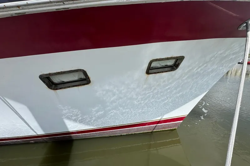 The Smithsunian Yacht Photos Pics 1989 DeFever 49 CPMY boat hull with red and white design, docked in water.