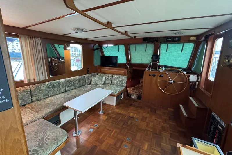 The Smithsunian Yacht Photos Pics 1989 DeFever 49 CPMY yacht interior with wood paneling, green curtains, and a spacious seating area.