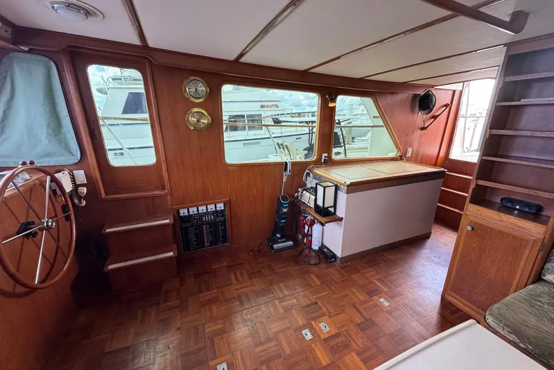 The Smithsunian Yacht Photos Pics 1989 DeFever 49 CPMY yacht interior with wooden helm, parquet flooring, and large windows.