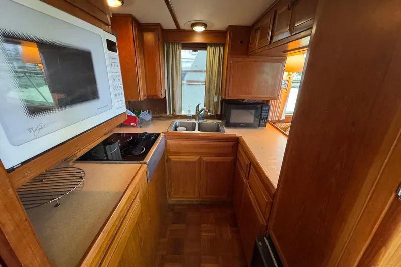 The Smithsunian Yacht Photos Pics 1989 DeFever 49 CPMY yacht kitchen with wooden cabinets, microwave, and stove.