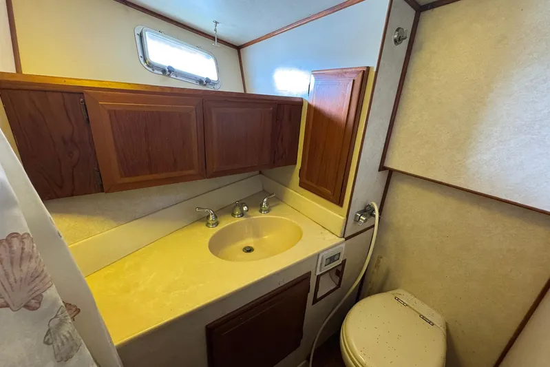 The Smithsunian Yacht Photos Pics 1989 DeFever 49 CPMY yacht bathroom with sink, wooden cabinets, and toilet.