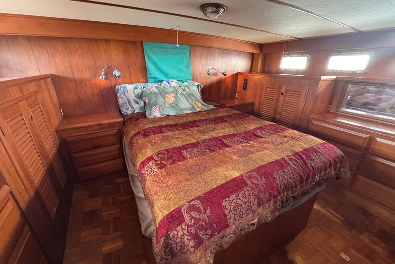 The Smithsunian Yacht Photos Pics Cozy bedroom in 1989 DeFever 49 CPMY yacht with wood paneling and colorful bedding.