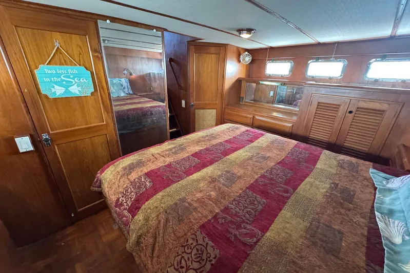 The Smithsunian Yacht Photos Pics Cozy bedroom in 1989 DeFever 49 CPMY yacht with colorful bedding and wooden interior.