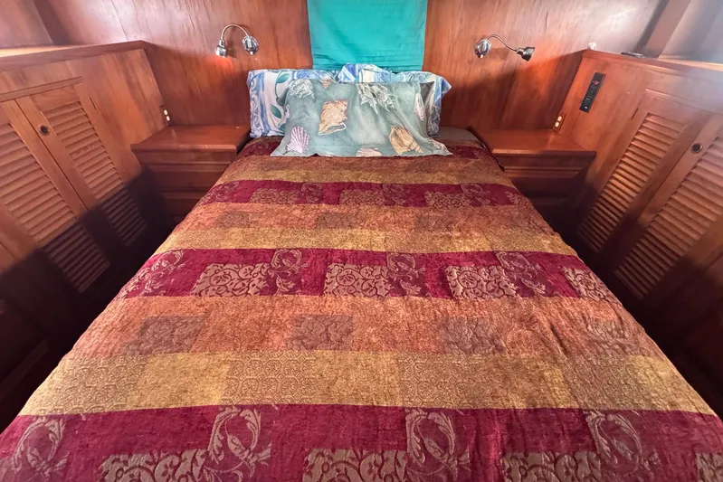 The Smithsunian Yacht Photos Pics Cozy bedroom on 1989 DeFever 49 CPMY yacht with colorful bedding and wooden accents.