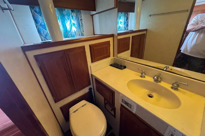 The Smithsunian Yacht Photos Pics Bathroom interior of 1989 DeFever 49 CPMY yacht with sink, mirror, and wooden cabinets.