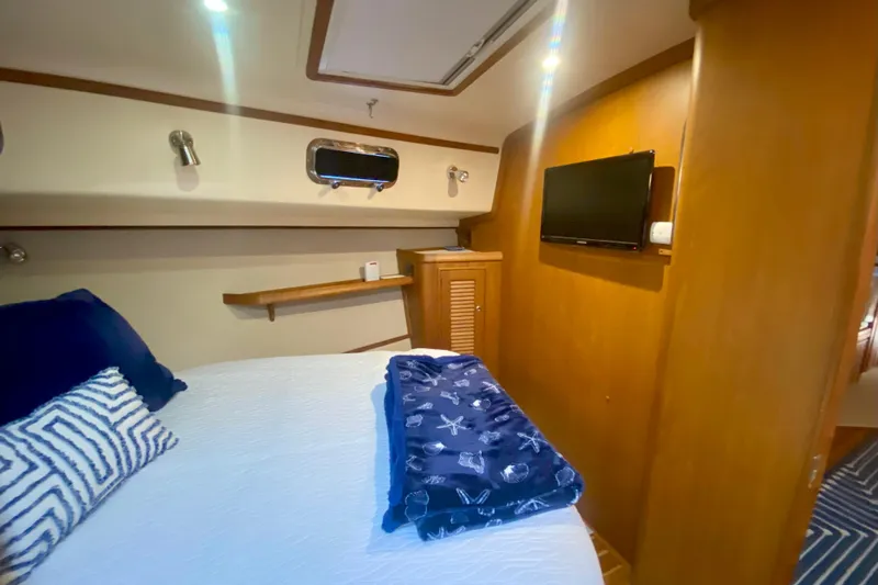 Second Wind Yacht Photos Pics Cozy cabin interior of 2006 Island Packet 440 yacht with bed, TV, and nautical decor.
