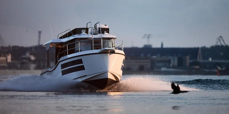  Yacht Photos Pics Modern Northman 1050 boat cruising on water, 2025 model, cityscape in background.