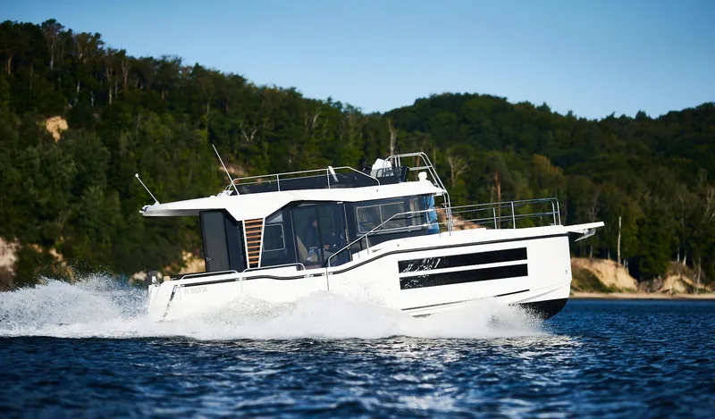  Yacht Photos Pics 2025 Northman 1050 boat cruising on a scenic lake with forested shoreline.