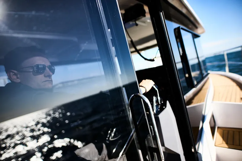  Yacht Photos Pics Man piloting Northman 1050 boat, 2025 model, with ocean reflection on window.