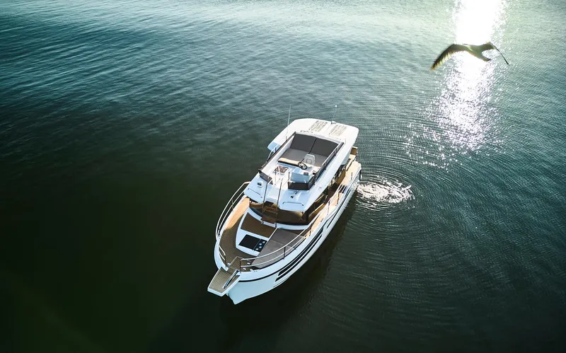  Yacht Photos Pics Aerial view of 2025 Northman 1050 yacht on calm water with a bird flying nearby.