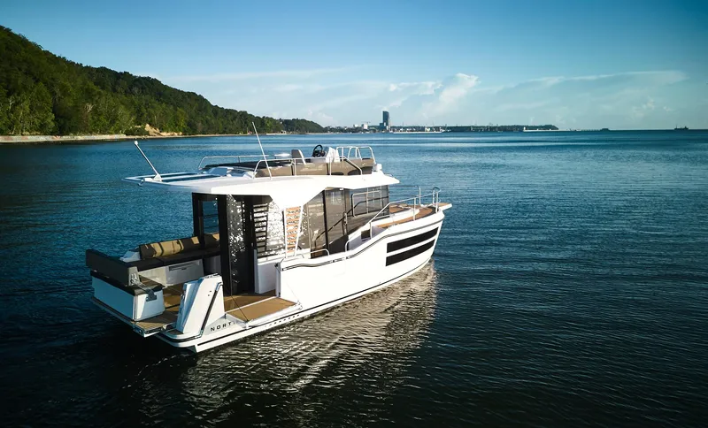  Yacht Photos Pics 2025 Northman 1050 yacht cruising on a serene lake with lush green shoreline.