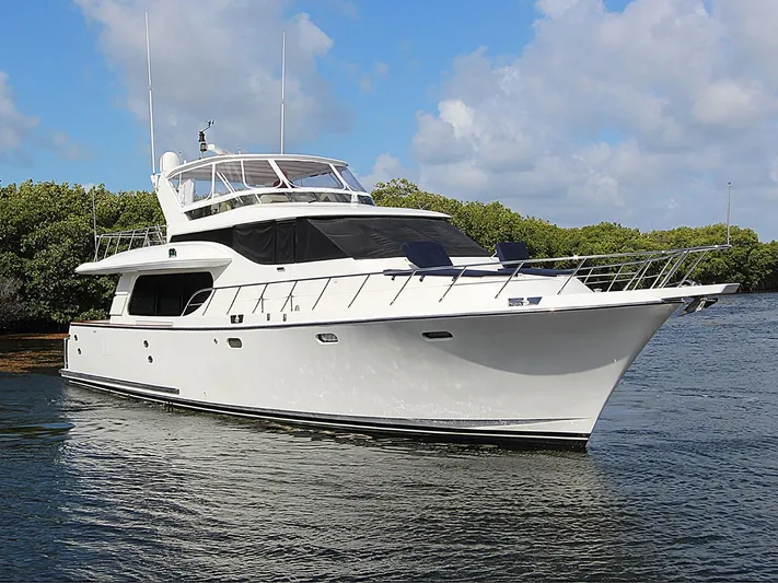 No Name Yacht Photos Pics 2001 Symbol 62 Pilothouse yacht on water, surrounded by lush greenery and blue sky.