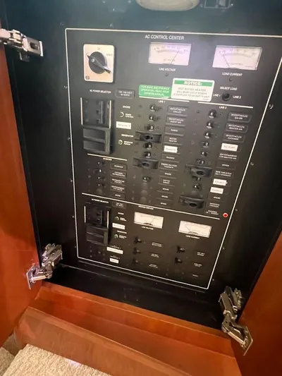 Roweboat Yacht Photos Pics 2006 Carver Voyager AC control panel with switches and gauges inside a wooden cabinet.