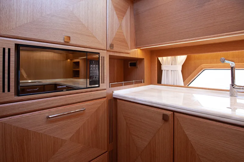 Mareluna Yacht Photos Pics Luxurious Vicem 55 yacht kitchen interior with wood cabinetry and modern appliances, 2023 model.