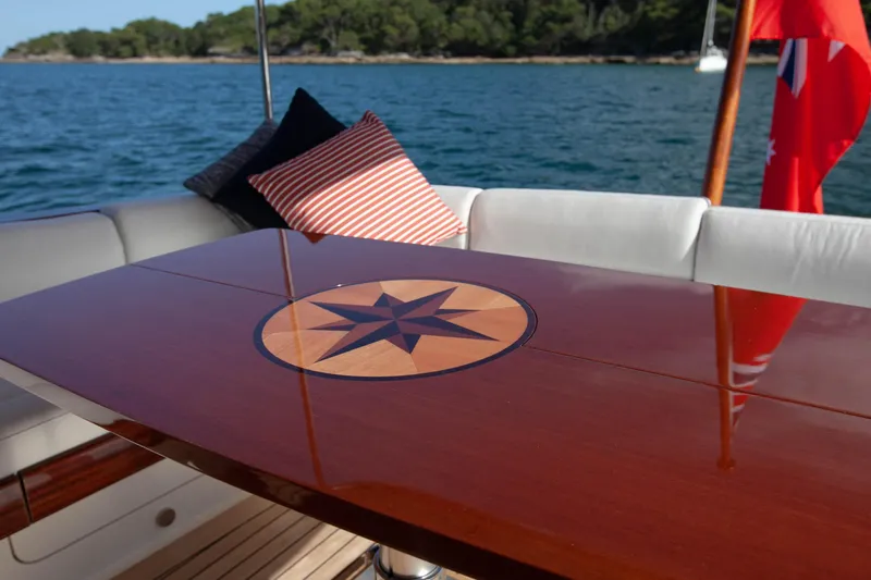 Mareluna Yacht Photos Pics Luxurious Vicem 55 yacht deck with elegant wooden table, nautical design, and scenic ocean view.
