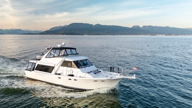 Seaclusion Yacht Photos Pics 1998 Bayliner 4788 Pilot House Motoryacht cruising on scenic waters with mountainous backdrop.