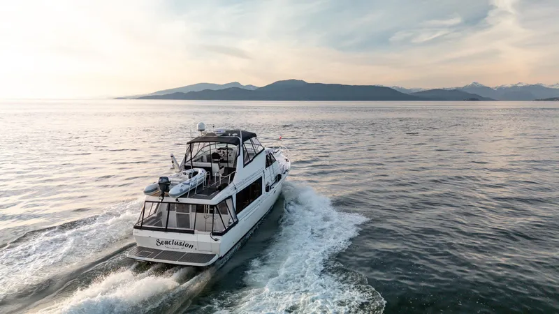 Seaclusion Yacht Photos Pics 1998 Bayliner 4788 Pilot House Motoryacht cruising on serene waters at sunset.