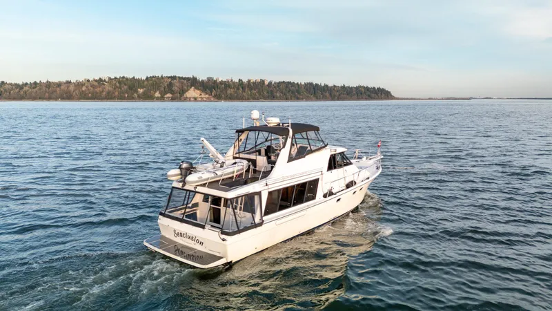 Seaclusion Yacht Photos Pics 1998 Bayliner 4788 Pilot House Motoryacht cruising on open water, scenic coastal background.