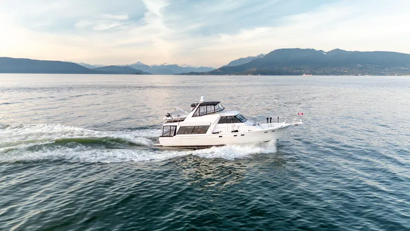 Seaclusion Yacht Photos Pics 1998 Bayliner 4788 Pilot House Motoryacht cruising on open water with scenic mountain backdrop.