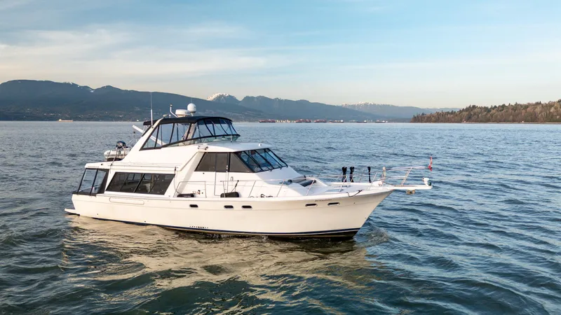 Seaclusion Yacht Photos Pics 1998 Bayliner 4788 Pilot House Motoryacht cruising on a scenic lake with mountains in the background.