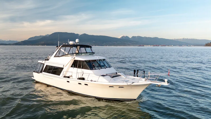 Seaclusion Yacht Photos Pics 1998 Bayliner 4788 Pilot House Motoryacht cruising on calm waters with mountainous backdrop.