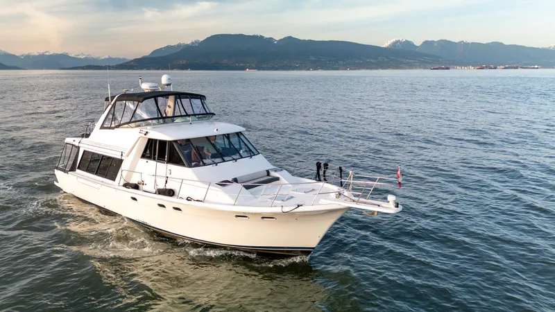 Seaclusion Yacht Photos Pics 1998 Bayliner 4788 Pilot House Motoryacht cruising on open water with mountainous backdrop.