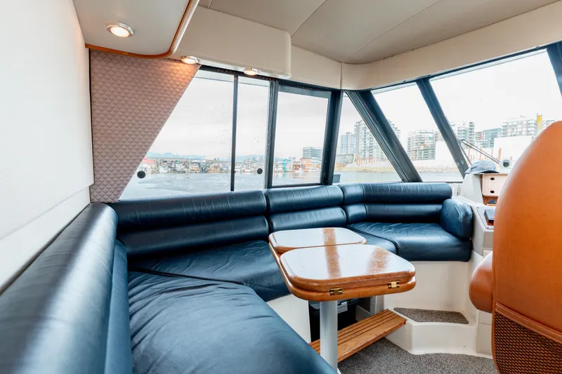 Seaclusion Yacht Photos Pics Interior of 1998 Bayliner 4788 Pilot House Motoryacht with blue seating and wooden table.