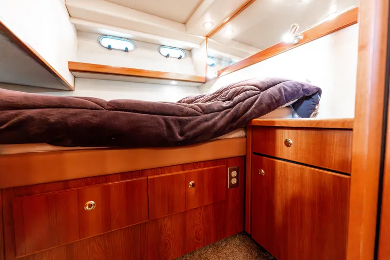 Seaclusion Yacht Photos Pics Cozy cabin interior of 1998 Bayliner 4788 Pilot House Motoryacht with wood cabinetry and bedding.