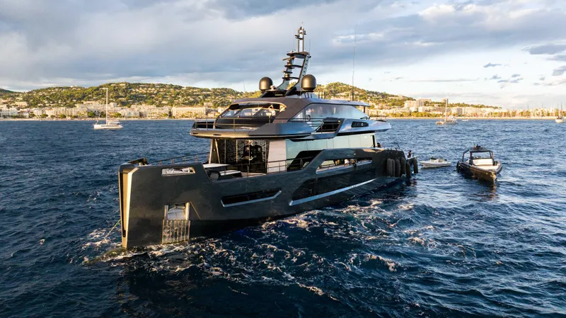 K+ Yacht Photos Pics Luxurious 2023 Maori M 125 yacht cruising on open water, with scenic coastal backdrop.