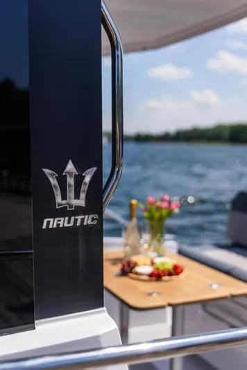  Yacht Photos Pics 2025 Nautic 880 yacht with elegant deck setup, featuring wine and flowers by the water.
