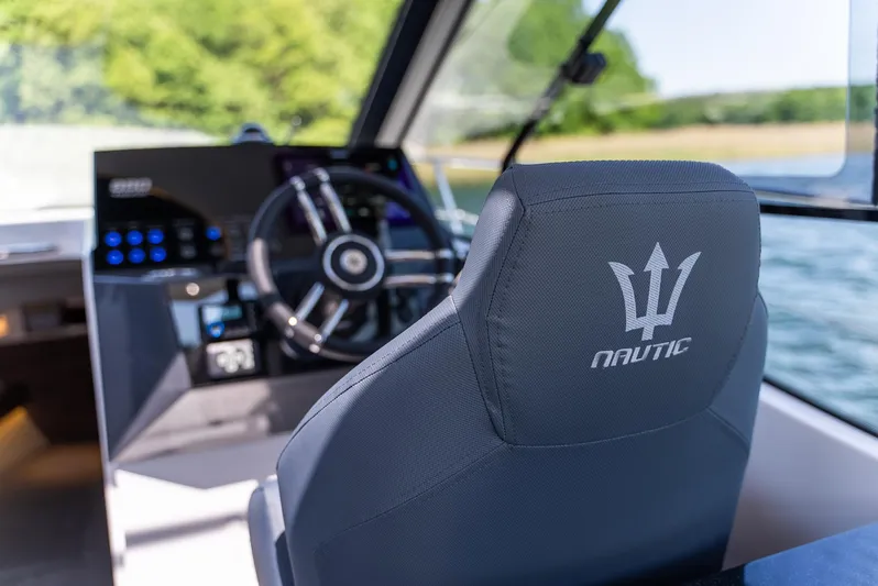  Yacht Photos Pics Interior of 2025 Nautic 880 boat, featuring steering wheel and branded seat.
