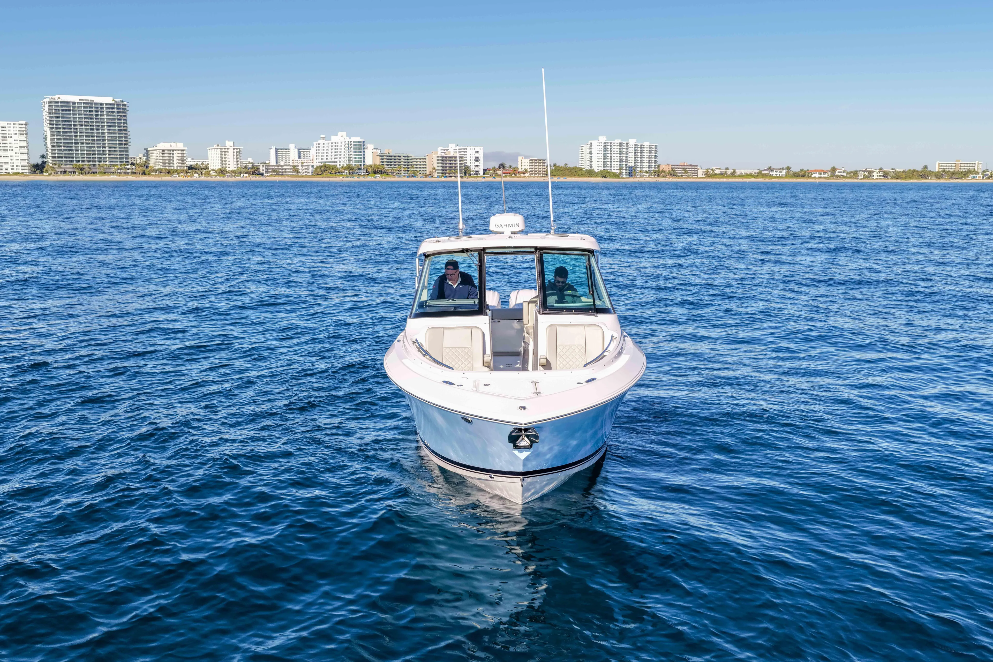 Endeavor Yacht Photos Pics 2023 Pursuit DC 295 Dual Console boat on open water with city skyline backdrop.